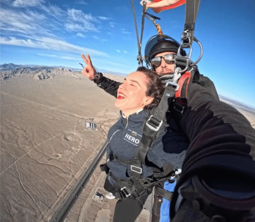 Photo of Julia tandem skydiving over a deserty area